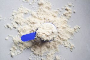 A top-down view of a scoop of whey protein powder on a wooden surface