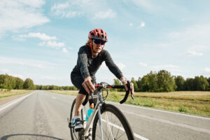 A female cyclist in sportswear riding a racing bike on the road outdoors.