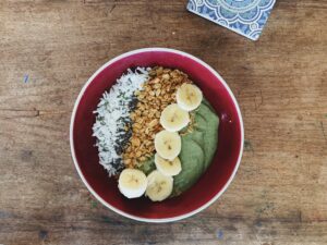 Vibrant acai bowl topped with fresh strawberries, bananas, blueberries, granola, and seeds, symbolizing healthy eating, on a neutral background.