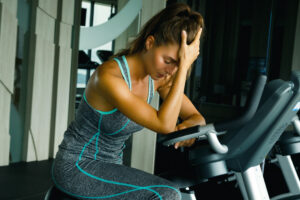 Woman in gym showing signs of overtraining fatigue