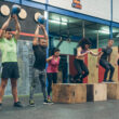 Group of athletes performing kettlebell exercises and box jumps in a workout session