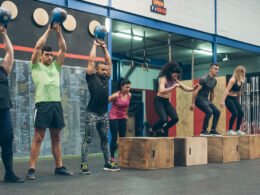 Group of athletes performing kettlebell exercises and box jumps in a workout session