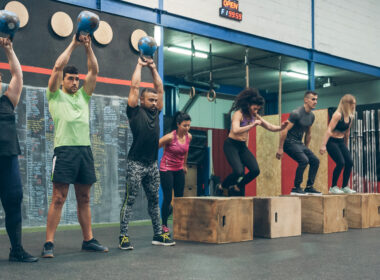 Group of athletes performing kettlebell exercises and box jumps in a workout session