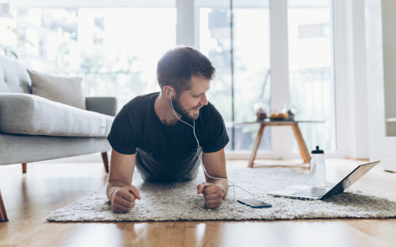 Handsome young man working out at home in the living room